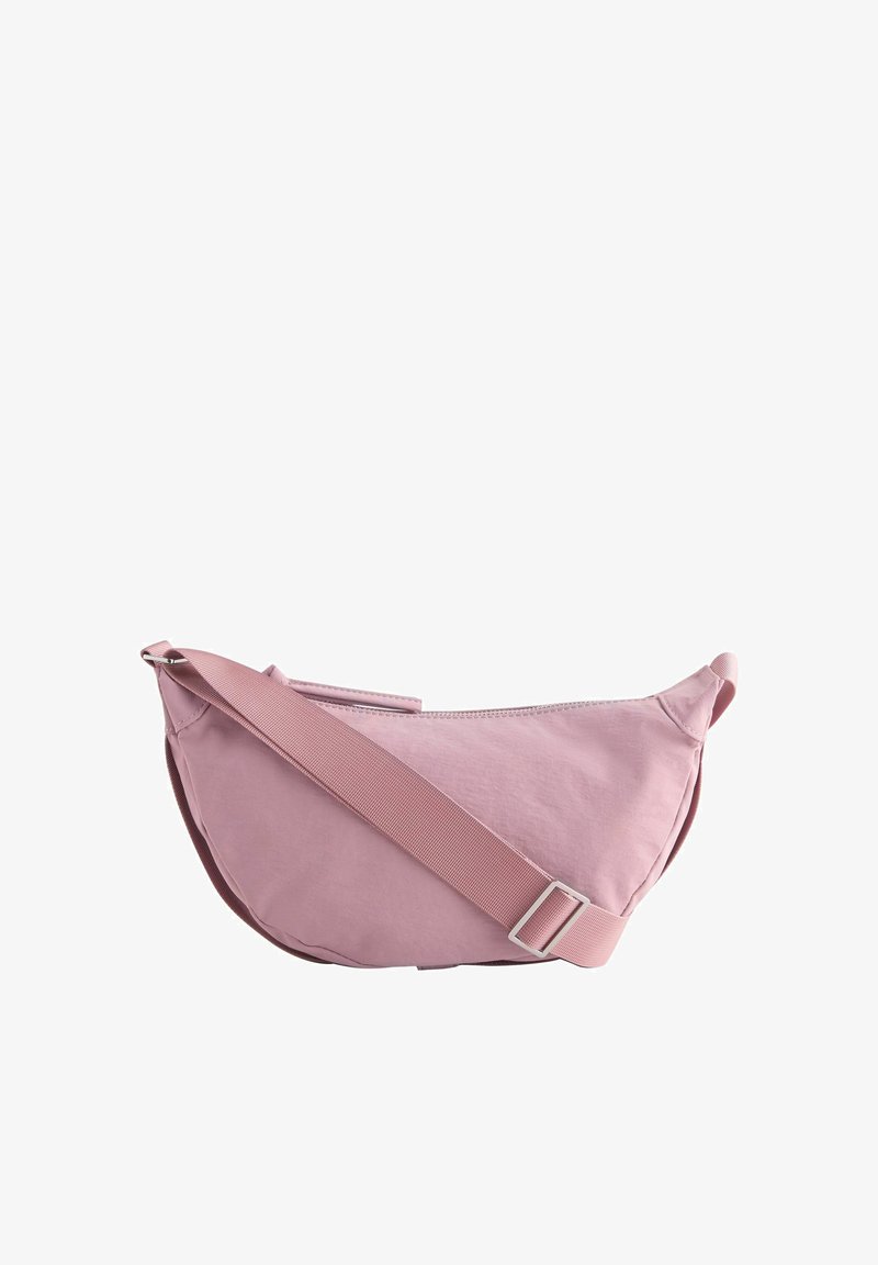 Hellrosa, halbmondförmige Umhängetasche mit verstellbarem breitem Riemen und Reißverschluss vor weißem Hintergrund.