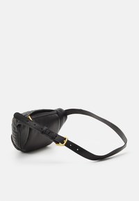 Mustasta nahkalaukusta, jossa on quiltsattu muotoilu, kaareva muoto ja kultasävyinen solkipanta. Materiaalilla on sileä pinta.