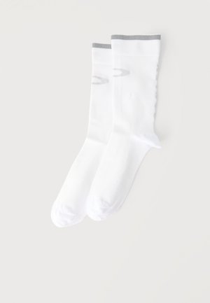 Paire de chaussettes blanches montantes avec un bord gris clair au niveau du poignet, posées à plat sur un fond clair uni.
