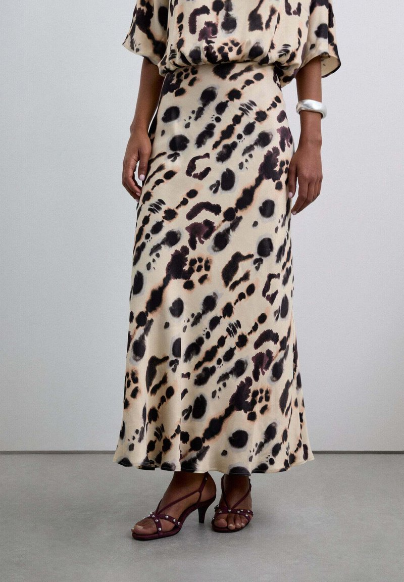 Falda midi de estampado de leopardo en una tela ligera, con una base beige y manchas negras y marrones, combinada con tacones marrones con tiras.