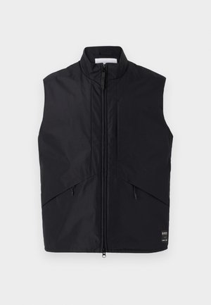 Musthave musterta, mis on valmistatud kerge ja veekindla materjali, millel on kõrge kaelus, esine zipper ja kaldus küljekotid.