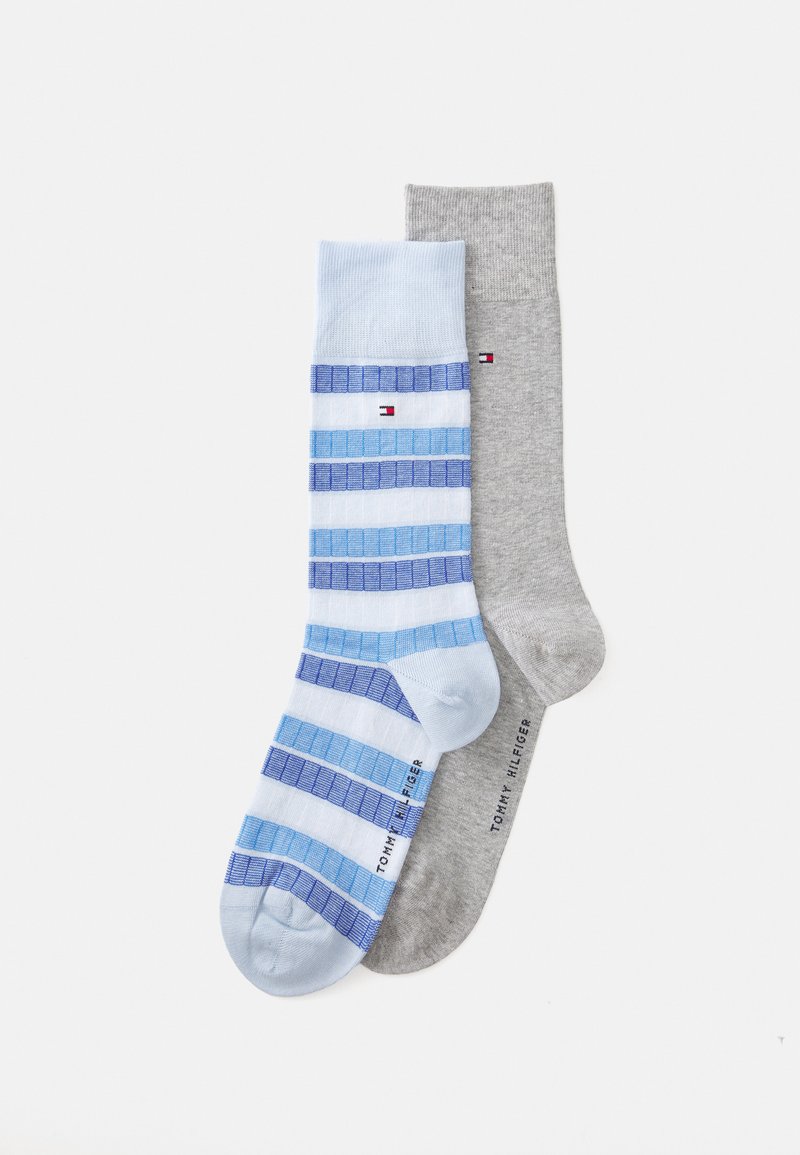 Deux paires de chaussettes : une rayée bleu avec des tons bleu clair et bleu foncé, et une autre unie grise. Chacune a une texture côtelée et une marque.