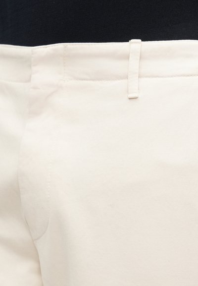 Béžové bavlněné kalhoty s plochým předním dílem, standardním pasem s poutkem a bočními lemy. Hladká textura s minimalistickým designem.