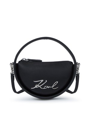Czarna półokrągła torebka z górnym suwakiem, srebrnym logo "Karl" na przodzie oraz odpinanym okrągłym uchwytem i paskiem na ramię.