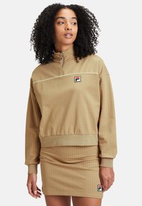 Felpa zip-up marrone con motivo a scacchi e gonna aderente coordinata. Presenta polsini a costine, vita elastica e patch con logo.