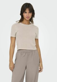 Beige kortærmet top med rund hals, parret med lysebrune bukser med elastisk talje. Blød tekstur, afslappet pasform, minimalistisk design.