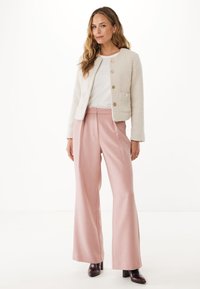 Textuur witte jas met gouden knopen, gecombineerd met lichtroze wijde broek en donkere hakken, op een witte achtergrond.