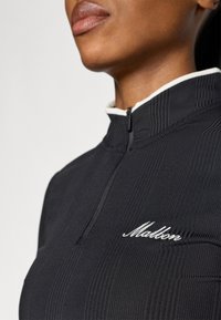 Top zip-up nero a coste con colletto alto e rifiniture bianche. Presenta un piccolo logo ricamato bianco sul petto. Finitura in tessuto testurizzato.