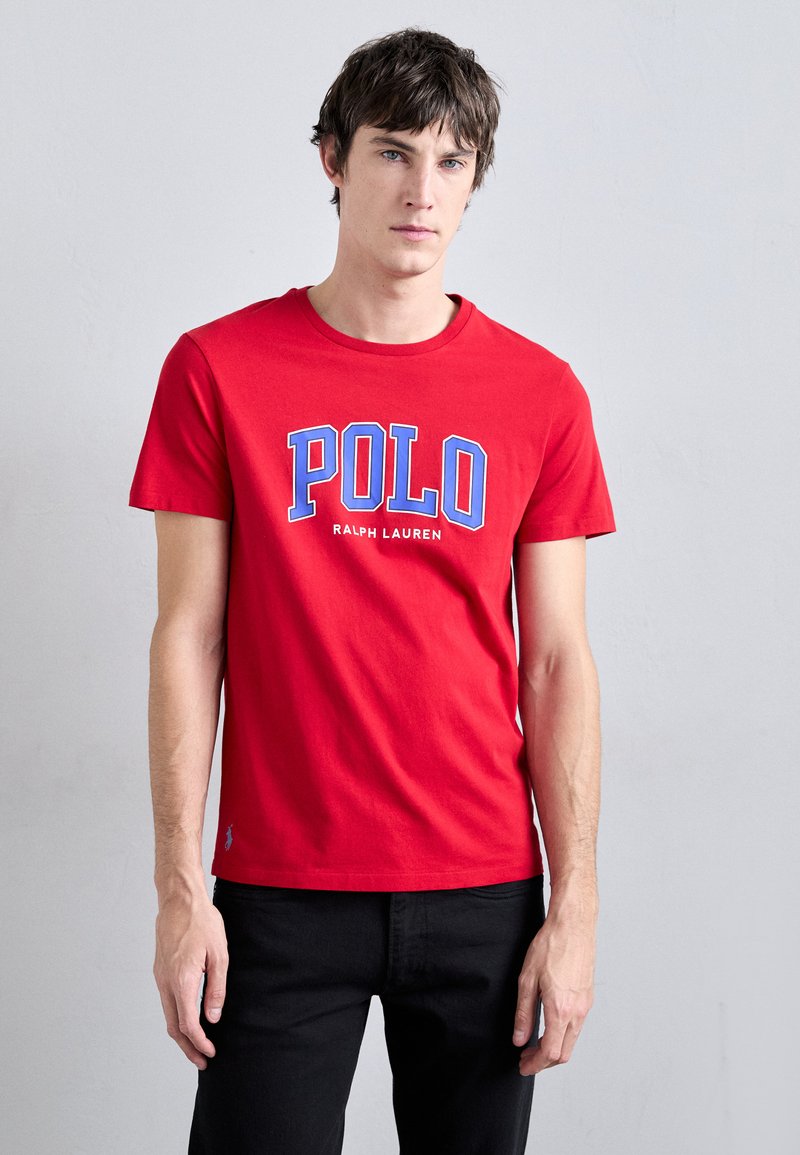 Piros pamut póló kék és fehér "POLO RALPH LAUREN" logóval, kerek nyakkal, rövid ujjú, és egy kis logóval az alsó elülső részen.