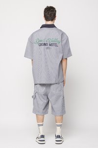 Striped short-sleeve shirt and cargo shorts in shades of blue, featuring "Devil's Walking Casino Motel" embroidered on the back in green and navy.