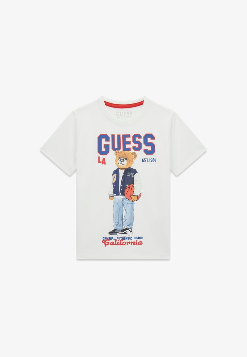 Άσπρο T-shirt με μια αρκουδίτσα σε varsity μπουφάν που κρατά ένα μπάσκετ, με τα κείμενα "GUESS," "LA" και "California" σε κόκκινο και μπλε χρώμα.