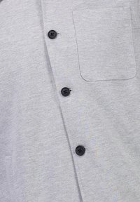 Grå button-up skjorta av texturerad tyg, med svarta knappar och en enda ficka på vänster sida.