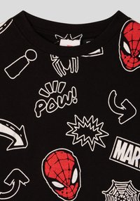 Czarna koszulka z różnorodnymi białymi grafikami w stylu kreskówkowym, w tym czerwonymi głowami Spider-Mana, napisem "POW!" oraz wzorami sieci. Miękka tkanina, okrągły dekolt.