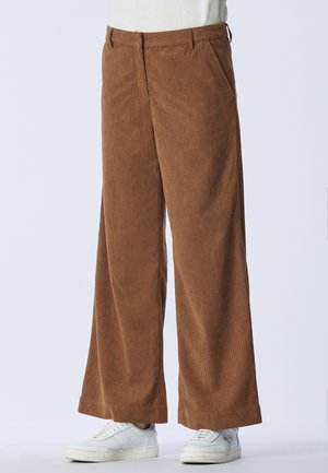 Pantaloni a gamba larga in cotone a coste marrone, dotati di due tasche laterali e una texture liscia, abbinati a sneakers bianche.