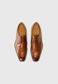 Zapatos de vestir de cuero marrón con una textura suave, punta afilada y dos ojetes. Presentan un diseño elegante y minimalista, y una suela duradera.