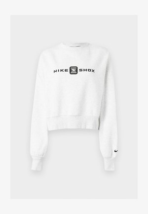Weißes, verkürztes Sweatshirt aus weichem Stoff. Mit schwarzem "NIKE SHOX"-Logo auf der Vorderseite und schwarzem Nike-Swoosh am Ärmel. Lange Ärmel mit gerippten Bündchen.