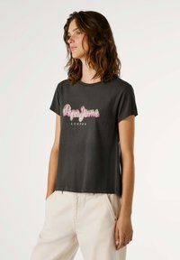 T-shirt de algodão cinza com mangas curtas, apresentando o texto do logo em rosa e branco "Pepe Jeans London" na parte da frente. Ajuste suave e casual.