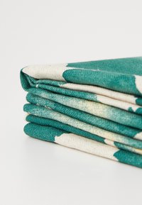 Tessuto piegato con un motivo color turchese e crema, che mette in evidenza una superficie morbida e strutturata con bordi lisci.