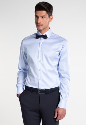 Hellblaues Langarmhemd mit Kentkragen, kombiniert mit einer schwarzen Fliege und dunkelblauen Hosen, die einen eleganten, gepflegten Look vermitteln.