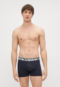 Fekete boxer alsónadrág, virágmintás derékkal, amelyen a márkanevének felirata található. Az anyag lágy megjelenésű, testhez simuló kialakítással és sima textúrával rendelkezik.