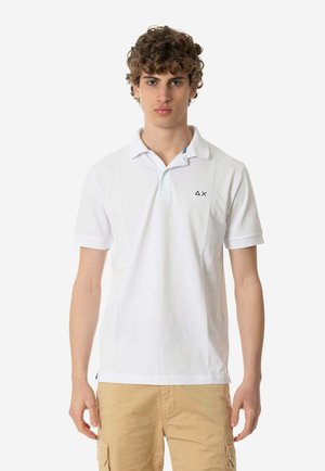 Polo bianca in cotone con colletto classico, maniche corte e un piccolo logo ricamato sul petto. Vestibilità su misura.