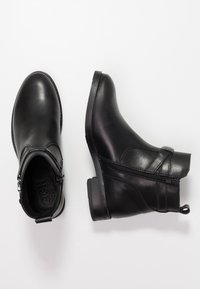 Black leather ankle boots featuring a side zipper, rounded toe, and a textured sole. Includes a loop for easy wear.
