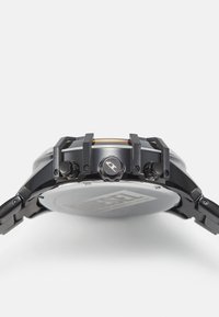 Schwarze Edelstahl-Uhr mit einem großen runden Gehäuse, zwei Druckknöpfen, einer auffälligen Krone und einem Raypane-Glas, das mit einer matten Oberfläche versehen ist.