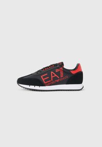 Schwarze und rote Sneakers mit einer glatten Oberseite und einem Wildlederakzent. Das Design umfasst die auffällige "EA7"-Markierung und eine weiße Gummisohle mit Traktionsmustern.