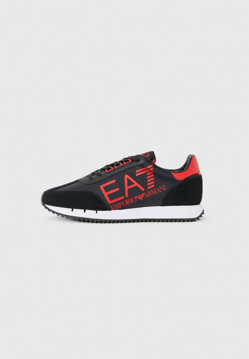 Schwarze und rote Sneakers mit einer glatten Oberseite und einem Wildlederakzent. Das Design umfasst die auffällige "EA7"-Markierung und eine weiße Gummisohle mit Traktionsmustern.