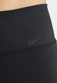Schwarze Sportleggings aus dehnbarem Material, mit einem dezenten schwarzen Nike-Logo. Der Bund hat flache Nähte für mehr Komfort.