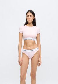 Ροζ βαμβακερό cropped τοπ με κοντά μανίκια και ταιριαστό στρινγκ, με λευκή ελαστική ταινία με το λογότυπο "Calvin Klein". Λεία υφή.