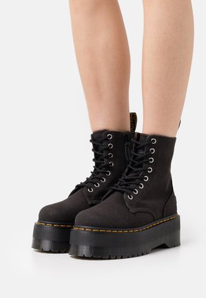 Czarne trampki za kostkę na grubej platformie, z metalowymi oczkami, czarnymi sznurówkami oraz żółtym przeszyciem wzdłuż podeszwy.