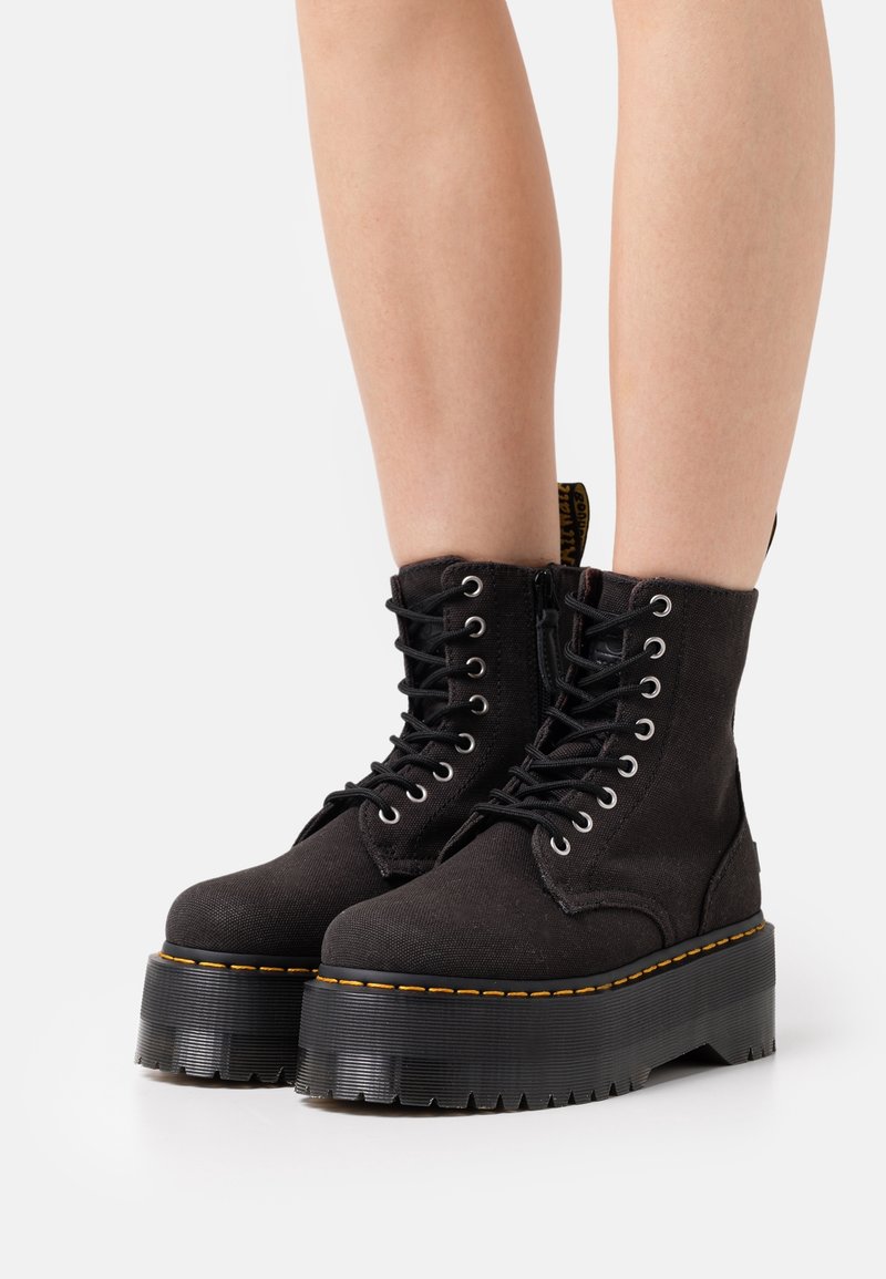 Czarne trampki za kostkę na grubej platformie, z metalowymi oczkami, czarnymi sznurówkami oraz żółtym przeszyciem wzdłuż podeszwy.