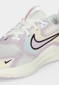 Λευκό και παστέλ μοβ παπούτσι για τρέξιμο Nike με επάνω μέρος από δίχτυ, σχεδιασμό με κορδόνια και μαύρο λογότυπο Nike swoosh στο πλάι και στην περιοχή των δαχτύλων.