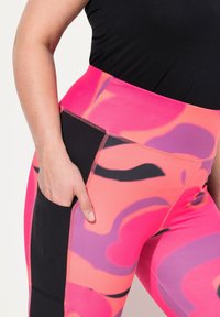 Högmidjade leggings med ett rosa och lila abstrakt mönster, svarta sidpaneler och en sidficka för bekvämlighet.