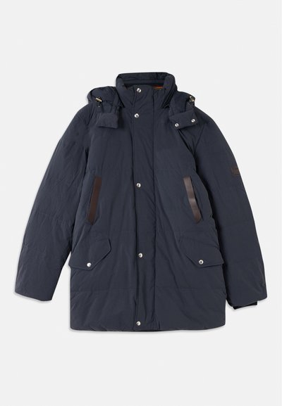 Parka acolchoada azul-marinho com colarinho alto, capuz destacável, detalhes em pele, dois bolsos frontais e fechos de botão de pressão.