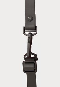 Black adjustable strap made of smooth, durable material, featuring a clip with a rectangular buckle and embossed logo detail.