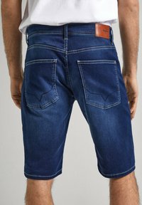 Pantalones cortos de mezclilla oscura con corte recto, que cuentan con dos bolsillos posteriores y costuras en contraste. Etiqueta de cuero en la cinturilla.