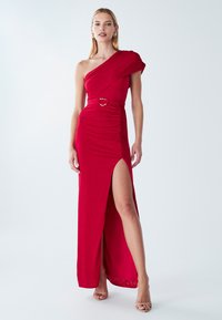Červené večerné šaty s jedným ramienkom, opaskom v páse, bočným rozparkom a nariasenou textúrou. Hladká látka s elegantnou siluetou a minimalistickými kovovými doplnkami.