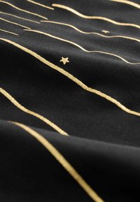 Tela negra con líneas horizontales doradas irregulares y una pequeña estrella dorada cerca del centro, mostrando textura y pliegues ligeros.