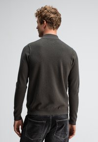 Leichter, dunkelgrüner Pullover mit ribbeltem Kragen und Bündchen, verfügt über lange Ärmel und eine glatte Textur. Die Rückansicht zeigt die Nähdetails.