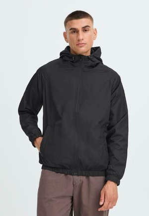 Svart hettegenser med full glidelås foran, elastiske mansjetter og strammet nederkant. Stoffet ser glatt ut med et lett design.