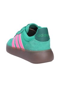 Baskets Adidas vertes avec des bandes roses, dessus en daim et cuir, et semelle épaisse marron, vues de l'arrière droit en angle.