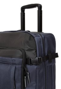 Maleta de viaje de tela azul marino con detalles en negro, mango retráctil resistente, múltiples bolsillos con cremallera y correas de compresión laterales.
