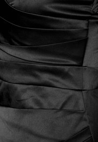 Svart klänning med ett texturerat satinmaterial, horisontella veck, slät yta och utan synlig hårdvara eller prydnader.