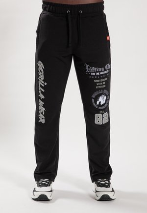 Schwarze Jogginghosen aus einem Baumwoll-Mix, mit metallgrauen Prints, Kordelzugbund und seitlichen Taschen. Akzente umfassen Markendetails.
