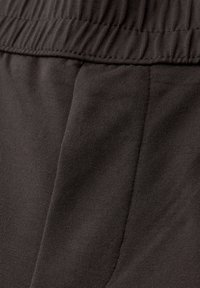 Close-up of dark gray fabric with elastic waistband and visible seam stitching, likely part of casual pants or shorts.