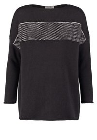 Pull en tricot noir à manches longues avec un panneau texturé blanc au niveau de la poitrine. Il présente un col large et simple ainsi que des poignets côtelés.