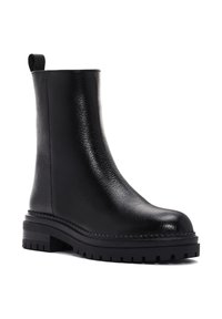 Botín de cuero negro hasta el tobillo con una textura suave, puntera redondeada y suela de goma negra gruesa con un patrón de agarre y una tira en la parte trasera.