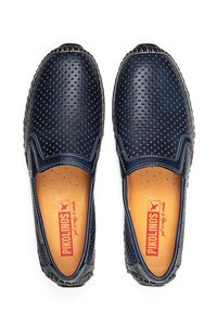 Marineblå perforerede lædersko med slip-on design, brun indersål og synlige sømme. Har rund tå og elastiske sidestykker for nem påtagning.